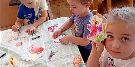 Powiększ grafikę: Troje dzieci przy stoliku koloruje listki