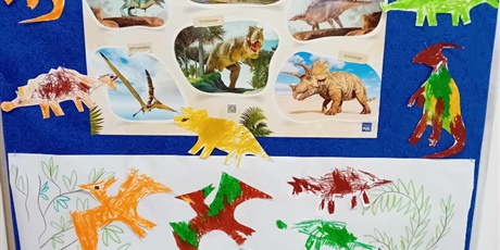 Powiększ grafikę: Na zdjęciu plakat z dinozaurami i dinozaury pokolorowane przez dzieci z grupy I
