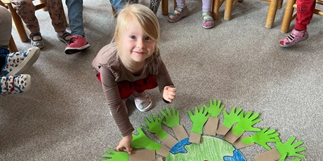 Powiększ grafikę: Dziewczynka z grupy I przykleja "swoje drzewko" do Ziemi.