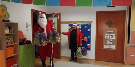 Powiększ grafikę: Pani Dyrektor pomaga Mikołajowi wnieść prezenty dla dzieci z grupy I