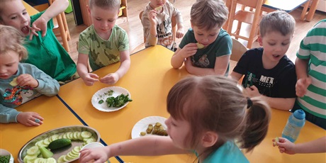 Powiększ grafikę: Dzieci z grupy II siedzą przy stolikach i zajadają ze smakiem zielone warzywa