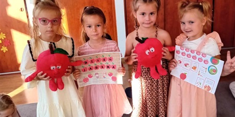 Powiększ grafikę: Na zdjęciu cztery dziewczynki z grupy III - trzymają w rączkach maskotki jabłuszka i prace plastyczne o jabłuszkach