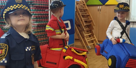 Powiększ grafikę: Dzieci w strojach policjanta, strażaka i strażnika miejskiego podczas zajęć na sali gimnastycznej "Autochodzik"