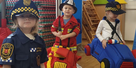 Powiększ grafikę: Dzieci w strojach policjanta, strażaka i strażnika miejskiego podczas zajęć na sali gimnastycznej "Autochodzik"