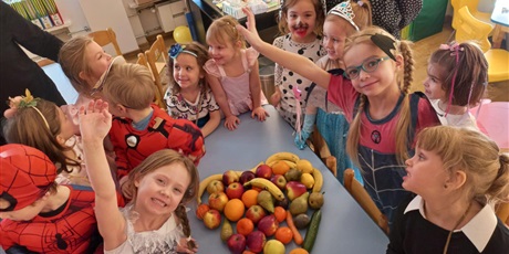 Powiększ grafikę:   Dzieci stoją dookoła stolika, na którym ułożone jest wielkie owocowe walentynkowe serce.