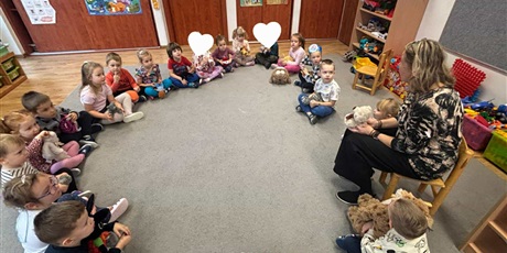 Powiększ grafikę: Dzień Misia w grupie II; pani Iwona siedzi na krześle, dzieci dookoła na dywanie
