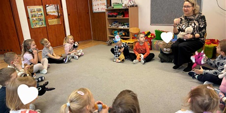 Powiększ grafikę: Dzieci z grupy II ze swoimi misiami; pani Iwona siedzi na krześle, dzieci w kółeczku