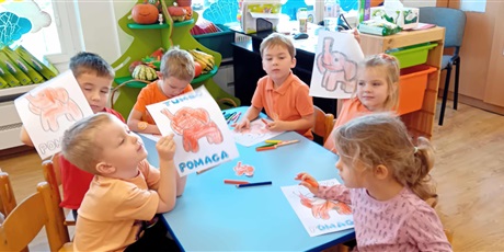 Powiększ grafikę: Dzieci przy stolikach kolorują Słonika Tumbo