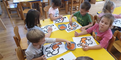Powiększ grafikę: Dzieci z grupy II siedzą przy stoliku i kolorują słonika Tumbo