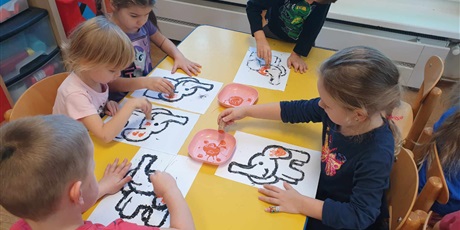Powiększ grafikę: Dzieci z grupy II siedzą przy stoliku i kolorują słonika Tumbo