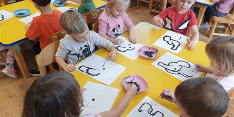 Powiększ grafikę: Dzieci z grupy II siedzą przy stoliku i malują farbami słonika Tumbo