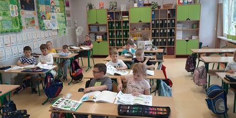 Powiększ grafikę: Ekoludki poznają salę lekcyjną, siedzą w ławkach i słuchają Pani