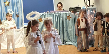 Powiększ grafikę: JASEŁKA - dzieci pięknie ubrane w stoje aniołków i pastuszków.Na pierwszym planie dwa aniołki, jedna dziewczynka z mikrofonem.