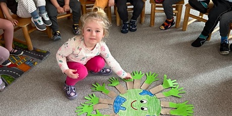 Powiększ grafikę: Dziewczynka z grupy I przykleja "swoje drzewko" do Ziemi.