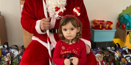Powiększ grafikę: Na zdjęciu dziewczynka z grupy I z Mikołajem. Dziewczynka trzyma w rączkach prezent, który wręczył jej Mikołaj. 