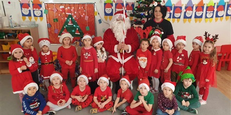 Powiększ grafikę: Na zdjęciu św. Mikołaj, pani Iza i dzieci z grupy II. Dzieci są ubrane w "mikołajowe" stroje 