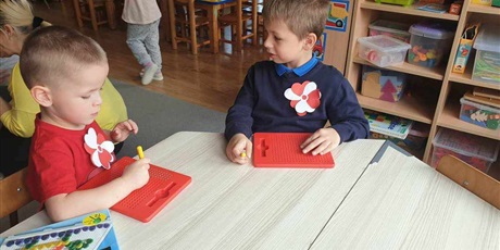 Powiększ grafikę: Na zdjęciu dwóch chłopców siedzi przy stoliku i bawią się tabliczkami magnetycznymi.
