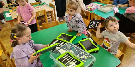 Powiększ grafikę: Na zdjęciu dzieci siedzące przy stolikach