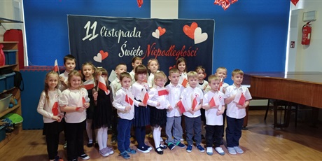 Powiększ grafikę: Na zdjęciu dzieci odświętnie ubrane trzymają w rączkach flagę Polski