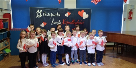 Powiększ grafikę: Na zdjęciu dzieci odświętnie ubrane trzymają w rączkach flagę Polski