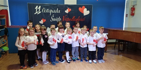 Powiększ grafikę: Na zdjęciu dzieci odświętnie ubrane trzymają w rączkach flagę Polski