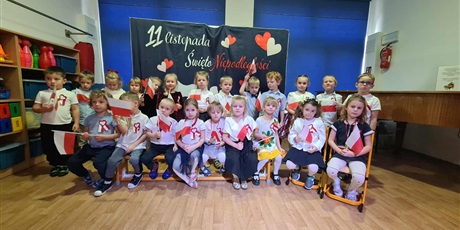 Powiększ grafikę: Kosmoludki podczas Dnia Niepodległości ubrane odświętnie trzymają w rączkach flagi Polski