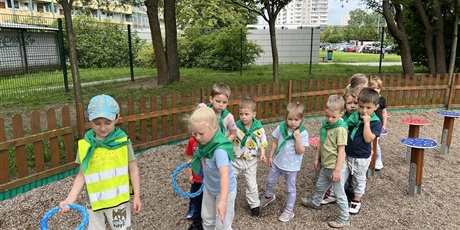 Powiększ grafikę: Na zdjęciu grupa dzieci wykonuje zadania sportowe