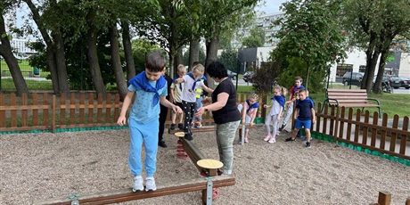 Powiększ grafikę: Na zdjęciu grupa dzieci wykonuje zadania sportowe
