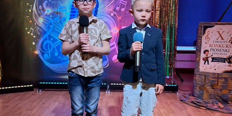 Powiększ grafikę: Na zdjęciu dwoje dzieci biorących udział w konkursie piosenki