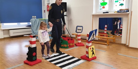 Powiększ grafikę: Pani ze Straży Miejskiej uczy dziewczynkę jak bezpiecznie przechodzić przez ulicę.