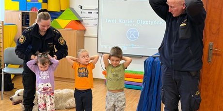 Powiększ grafikę: Dzieci, pracownicy Straży Miejskiej i pies Marley na sali gimnastycznej podczas zajęć edukacyjnych