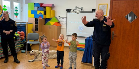 Powiększ grafikę: Dzieci, pracownicy Straży Miejskiej i pies Marley na sali gimnastycznej podczas zajęć edukacyjnych
