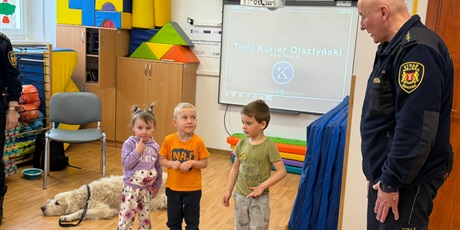 Powiększ grafikę: Dzieci, pracownicy Straży Miejskiej i pies Marley na sali gimnastycznej podczas zajęć edukacyjnych