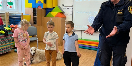 Powiększ grafikę: Dzieci, pracownicy Straży Miejskiej i pies Marley na sali gimnastycznej podczas zajęć edukacyjnych