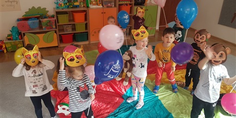 Powiększ grafikę: Dzieci z grupy I tańczą w maskach i trzymają w rączkach kolorowe balony